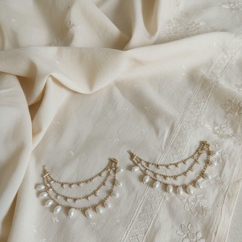Pearl and gold jewelry on a textured beige fabric background