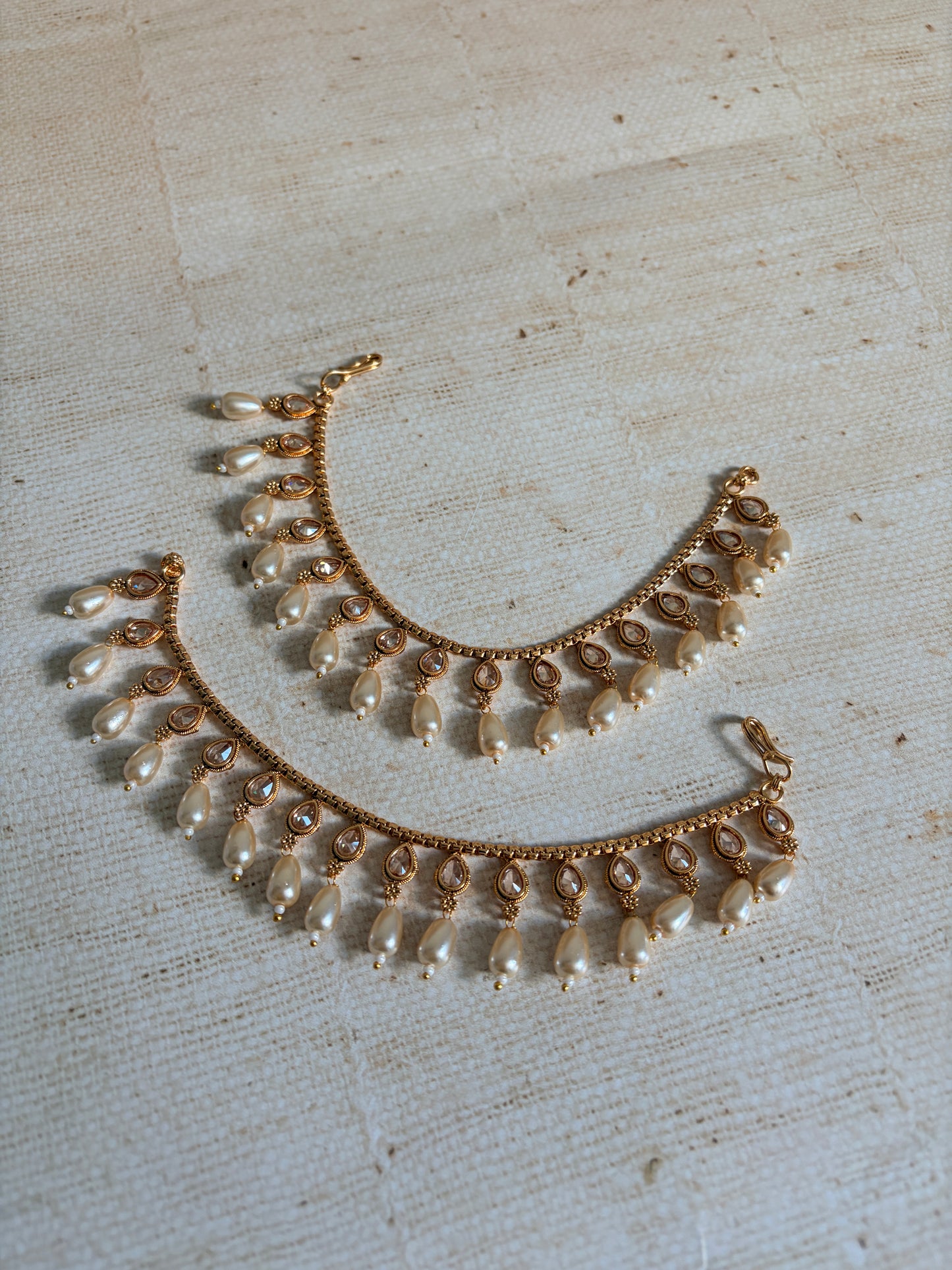 Gold and pearl necklace on a textured beige background