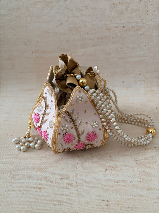 Decorative heart-shaped object with floral patterns and pearl accents on a beige background