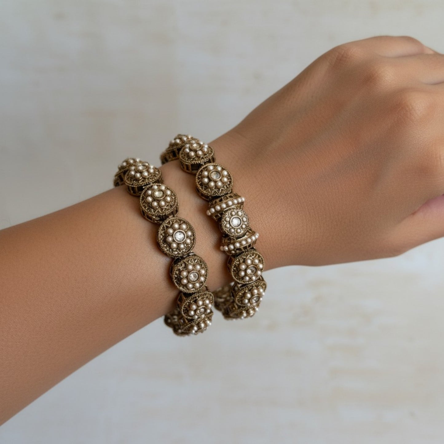Gold bracelet on a wrist against a neutral background