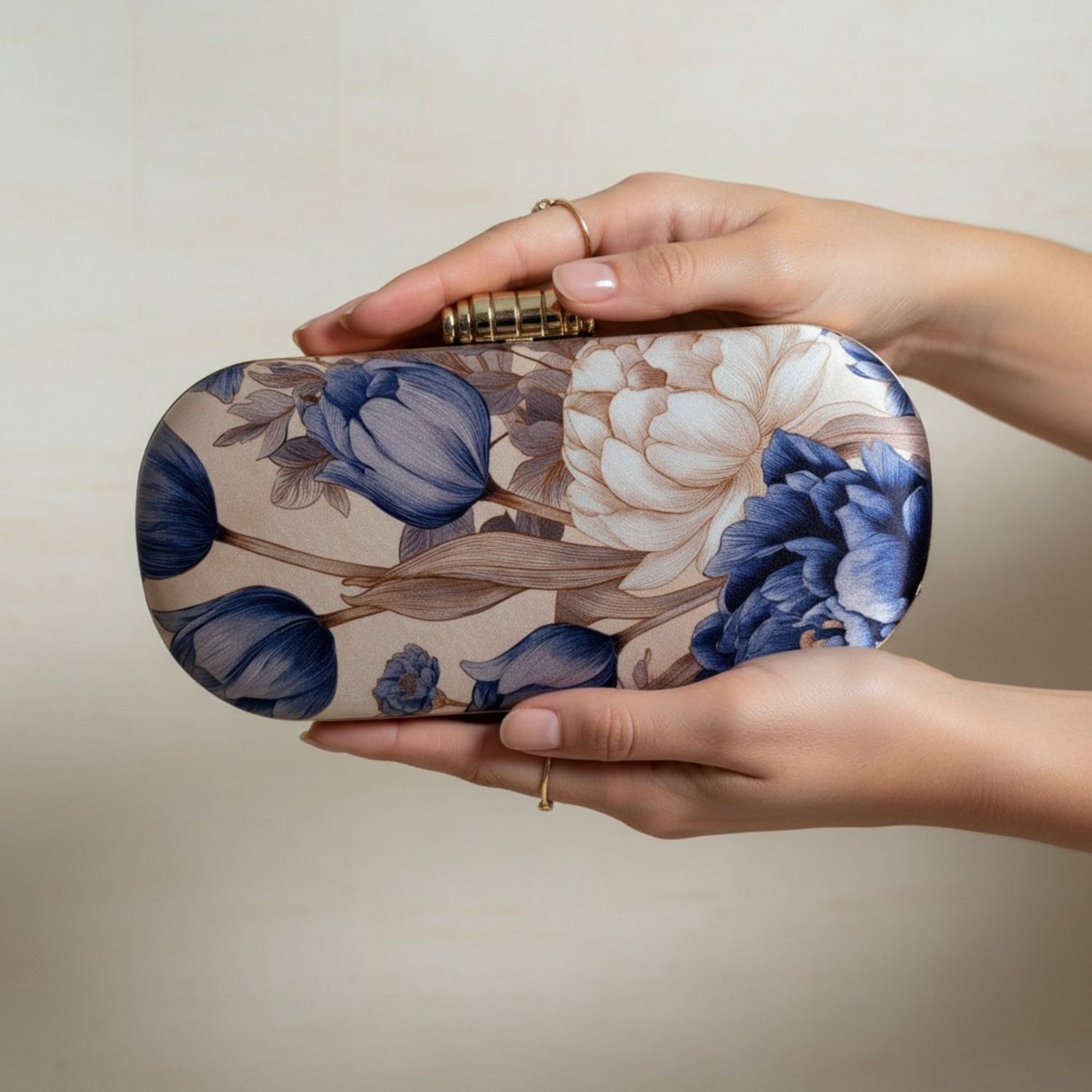 Floral patterned clutch held by a hand against a neutral background