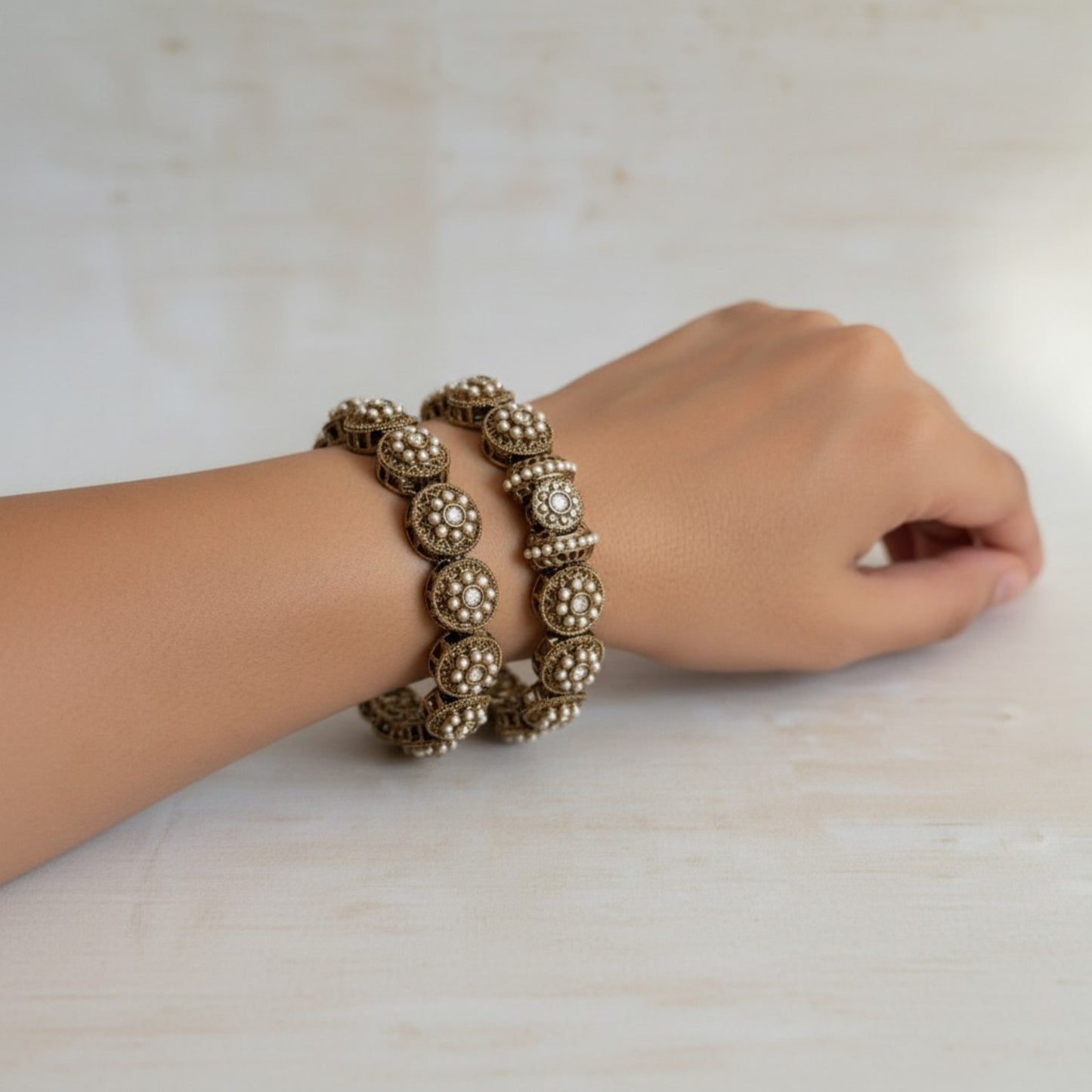 Gold bracelet on a wrist against a neutral background