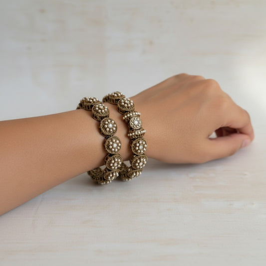 Gold bracelet on a wrist against a neutral background