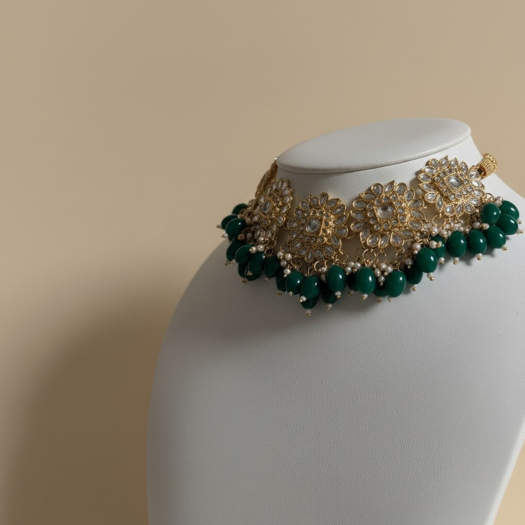 Gold and green beaded necklace on a mannequin bust against a beige background