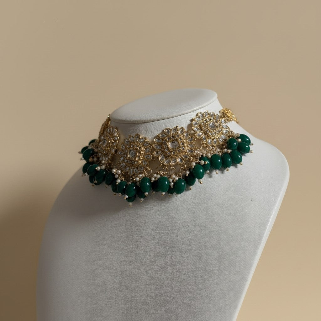 Decorative necklace with green beads and gold accents on a mannequin bust against a beige background
