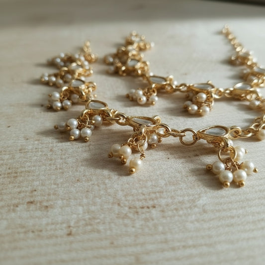 Gold necklace with pearl charms on a light wooden surface