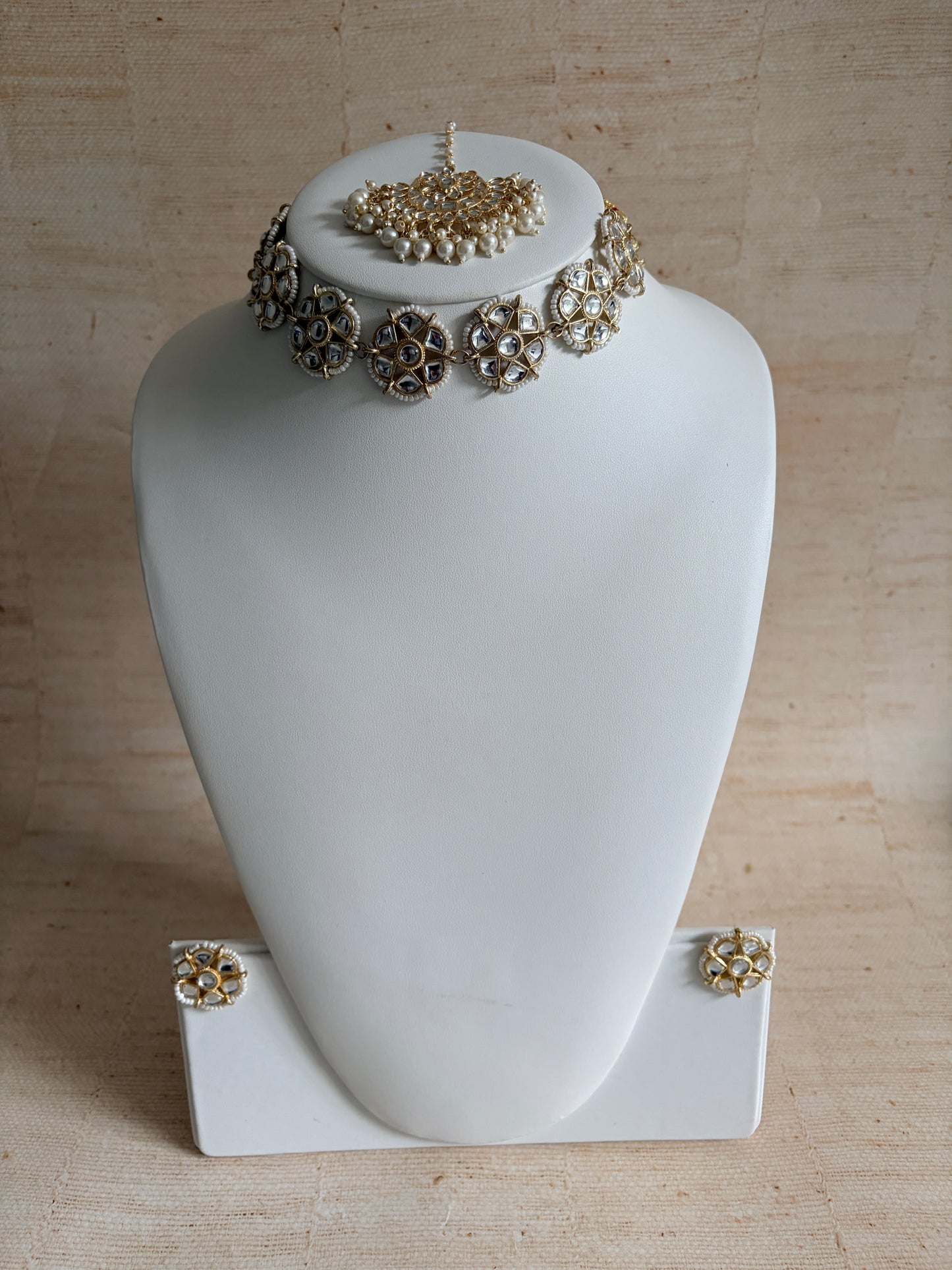 Decorative headband with floral designs on a mannequin head against a beige background