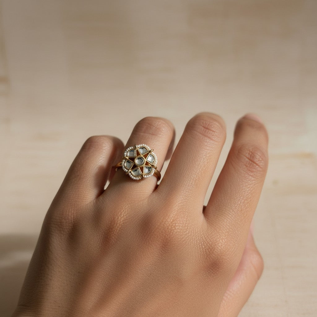Gold ring with a floral design on a hand against a beige background