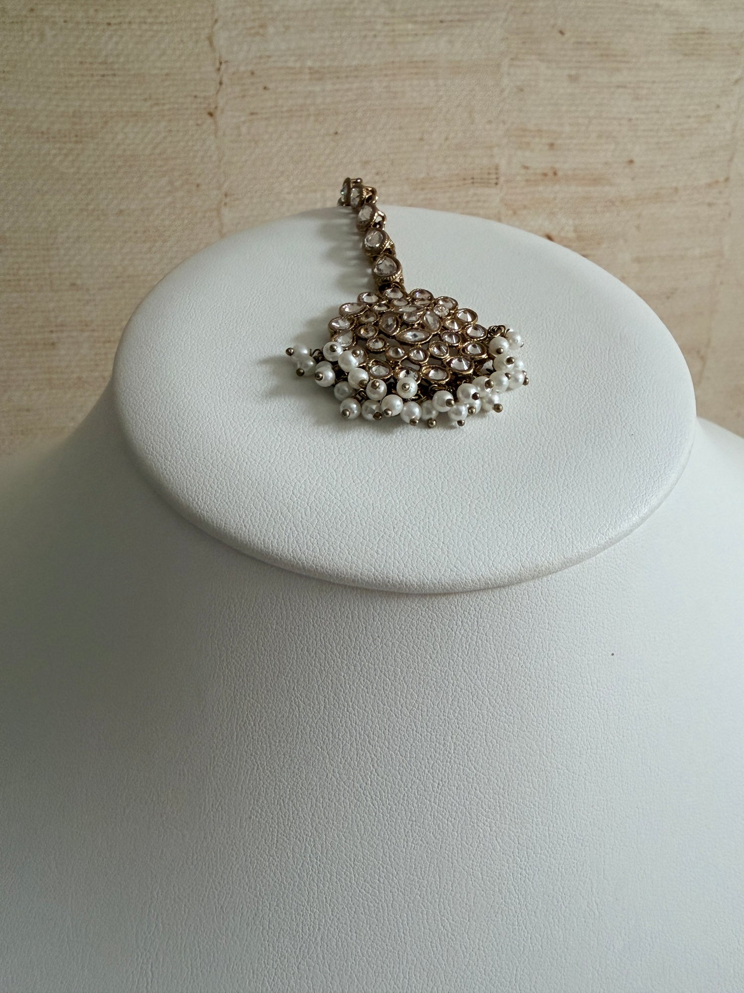 Pearl necklace on a white jewelry display stand against a neutral background