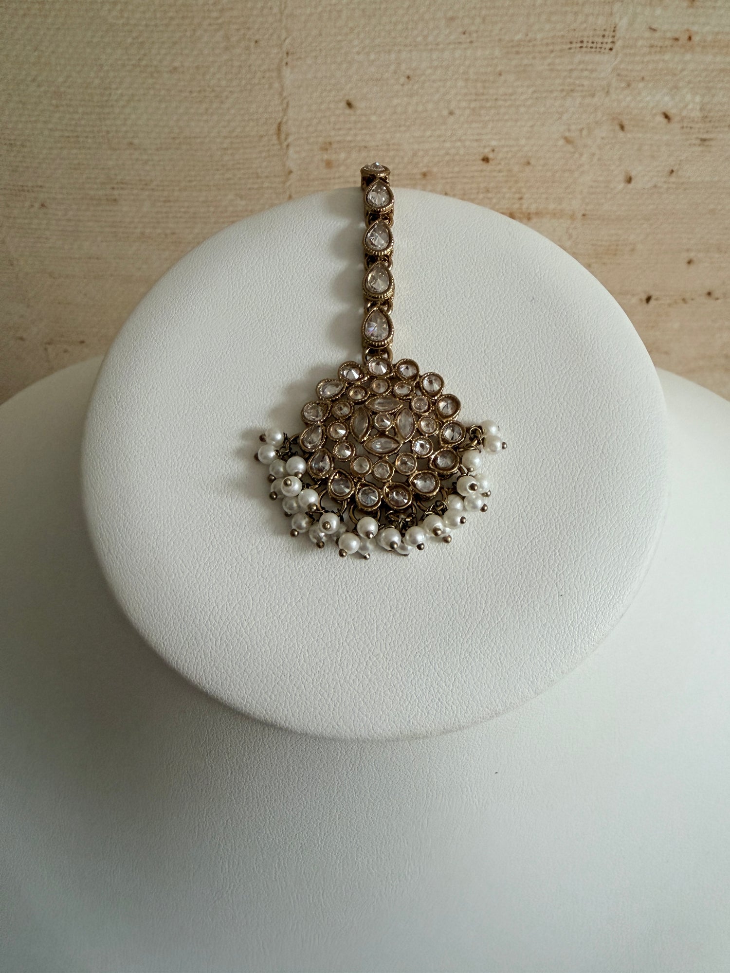 Decorative key-shaped object with pearls on a white cushion against a wooden background