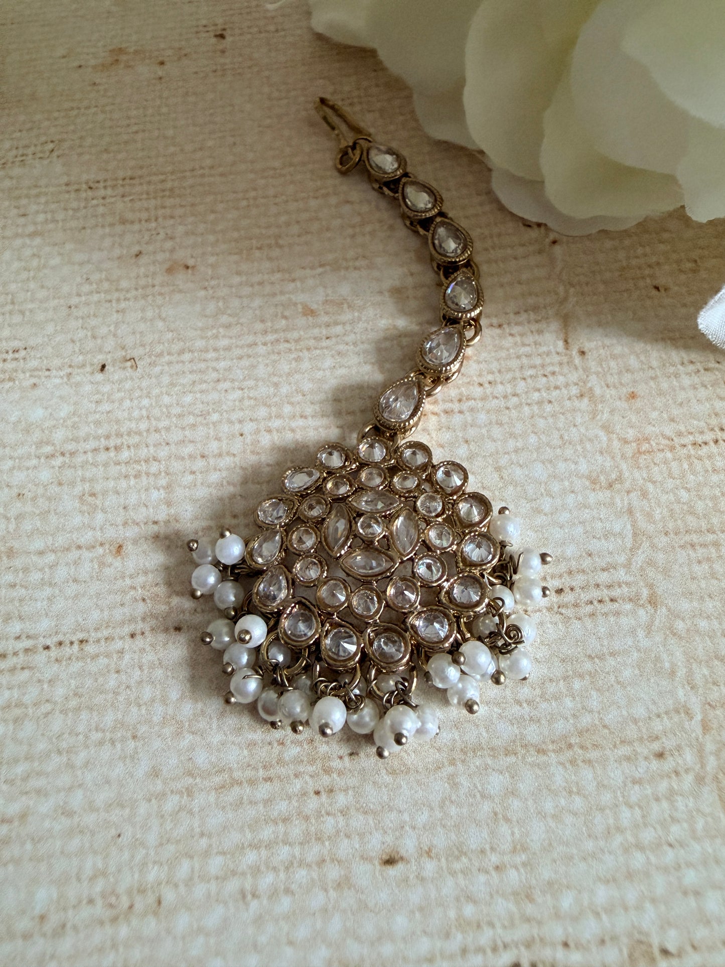 Decorative brooch with pearls and crystals on a textured beige background