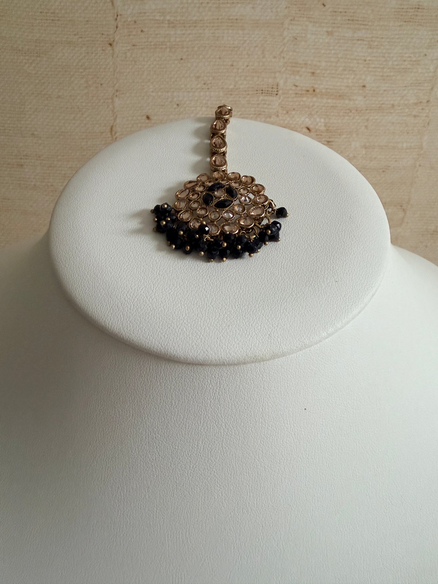 Bracelet with black beads on a white cushion against a beige background