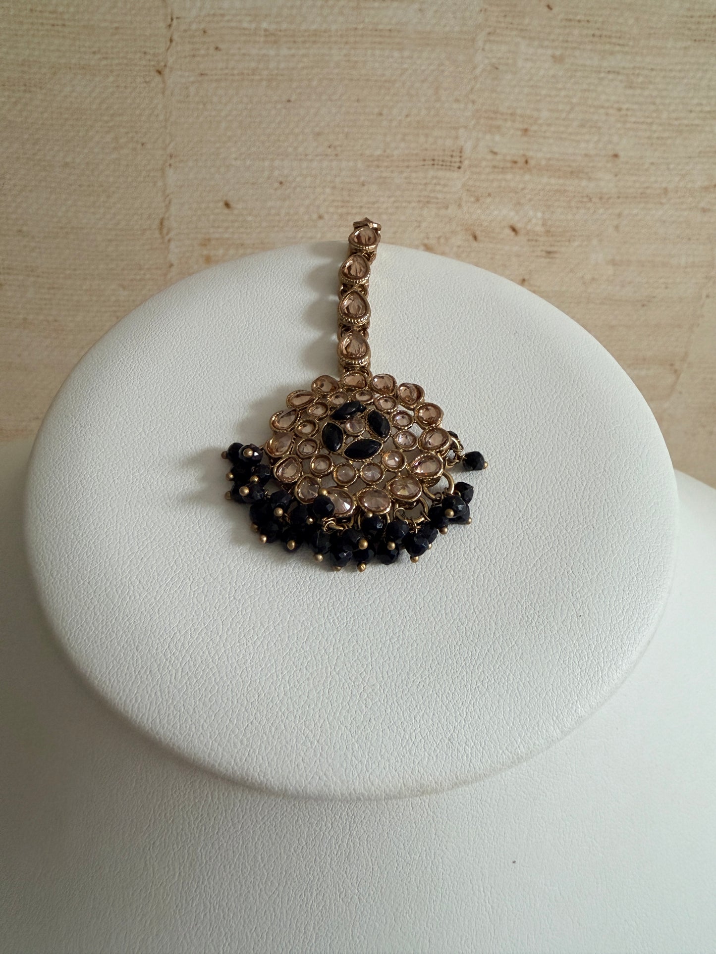 Bracelet with black and gold stones on a white cushion