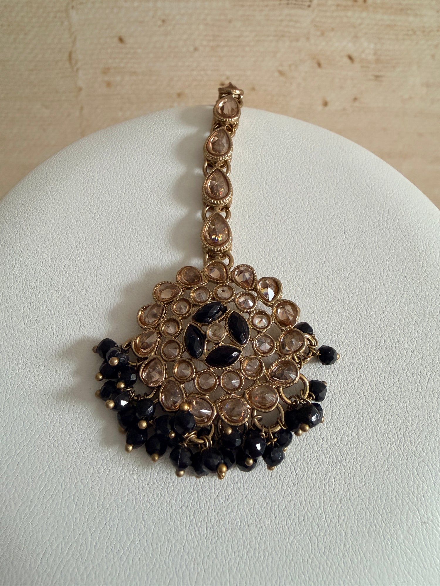 Decorative hair accessory with gold and black beads on a white background