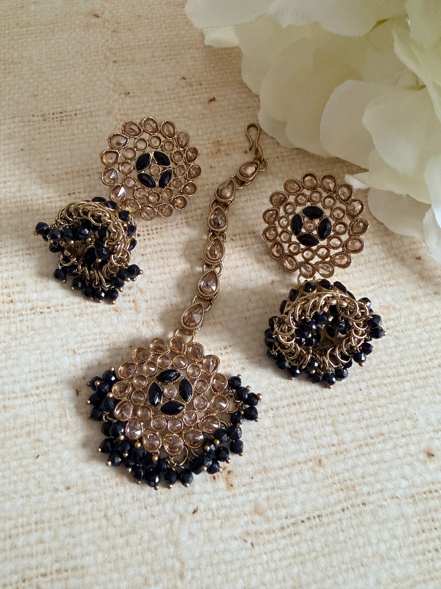 Jewelry set with gold and black beads on a textured beige surface