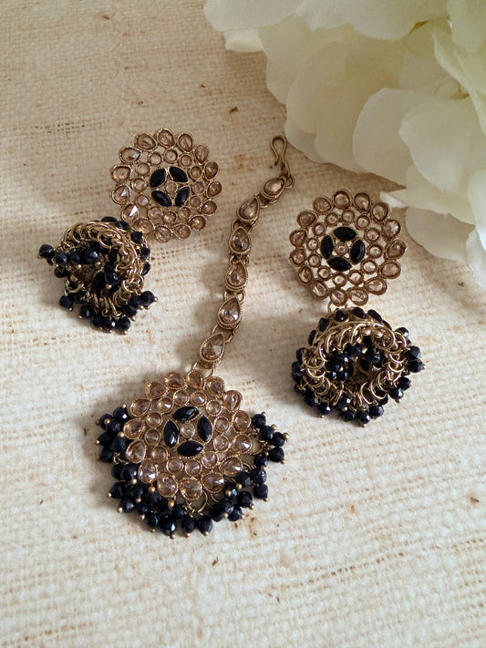 Jewelry set with gold and black beads on a textured beige surface