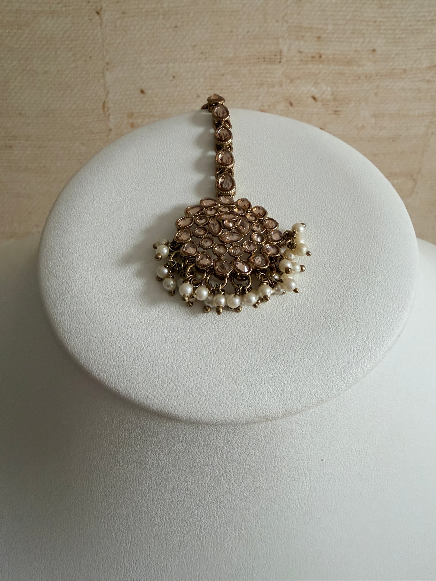 Bracelet with pearls on a white cushion against a beige background