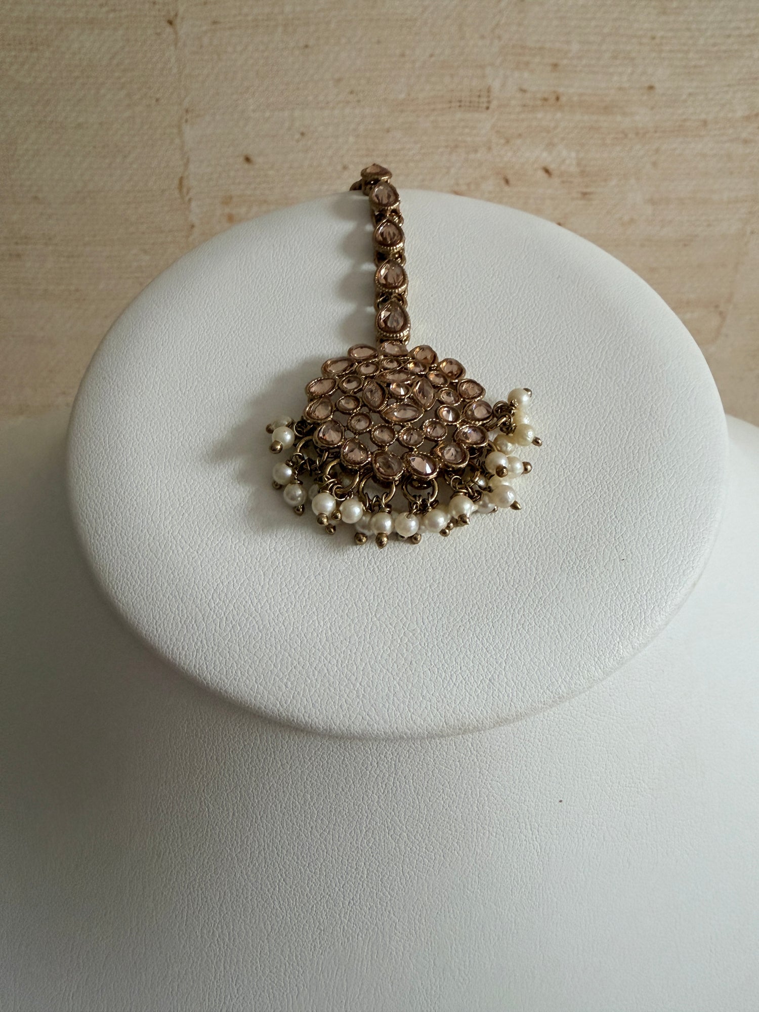 Bracelet with pearls on a white cushion against a beige background