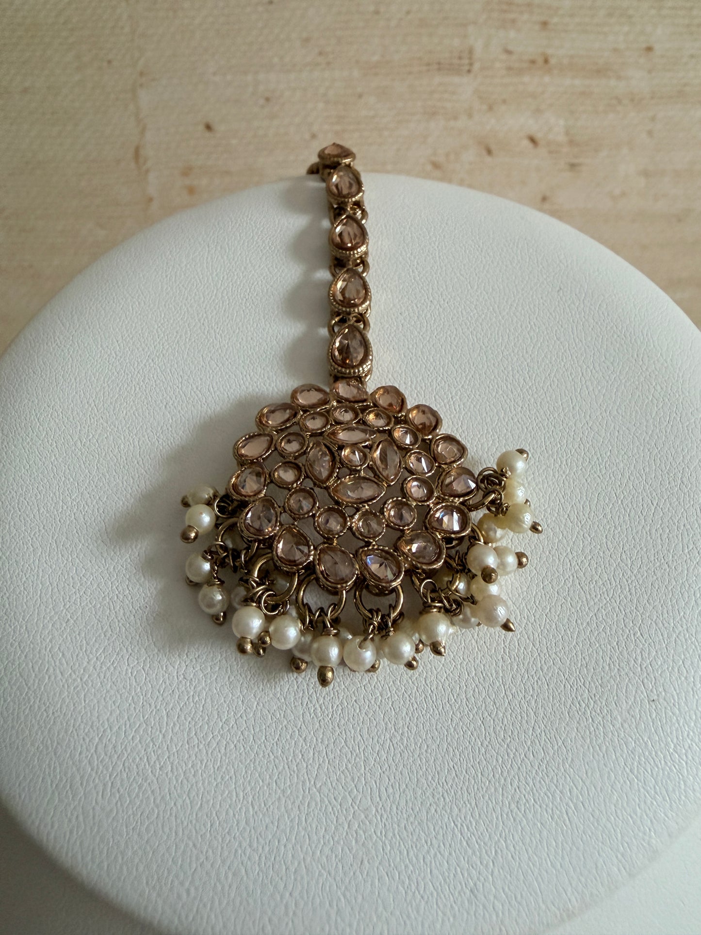 Jewelry set with pearls and rose gold accents on a white stand.