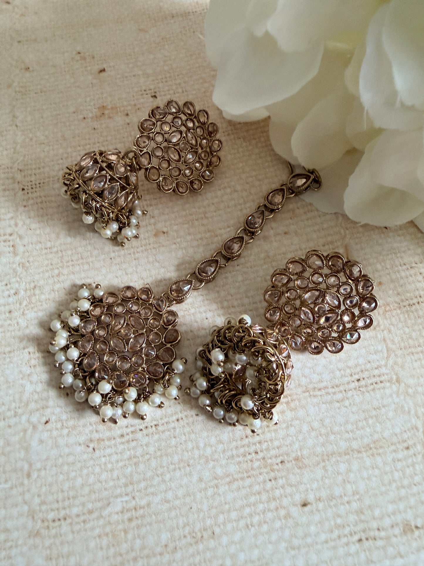 Vintage-style jewelry set with pearls on a textured fabric background
