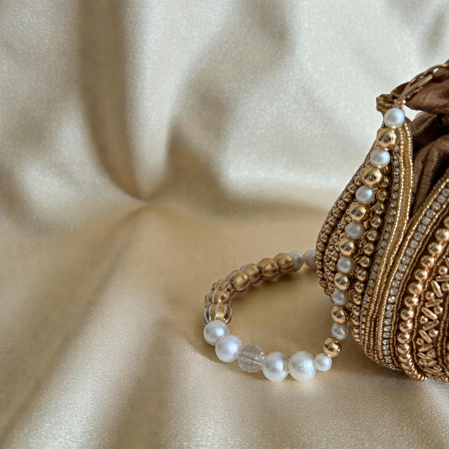 Gold bracelet with pearl beads on a beige fabric background