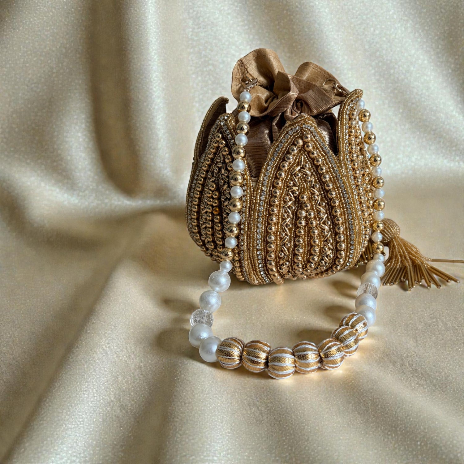 Decorative handbag with pearl bracelet on a beige fabric background