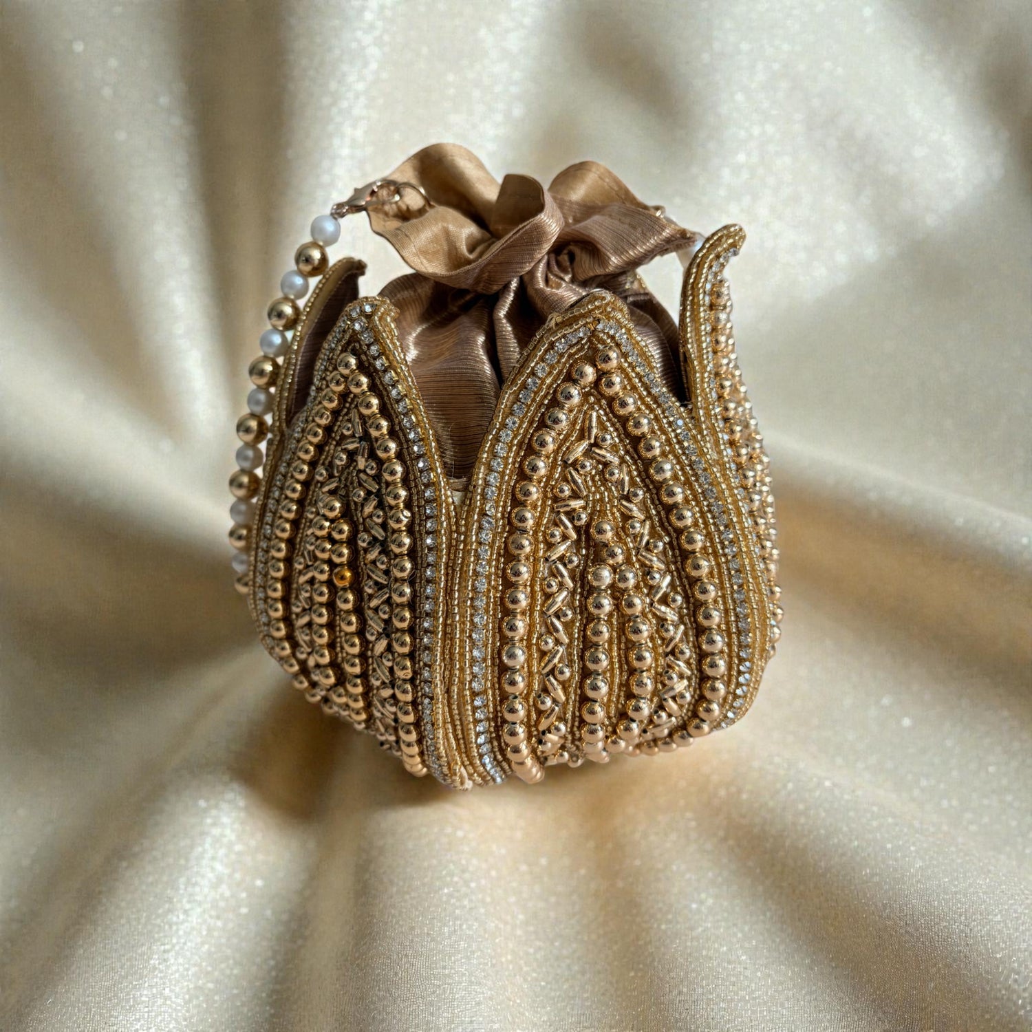 Decorative gold purse with intricate patterns on a beige fabric background