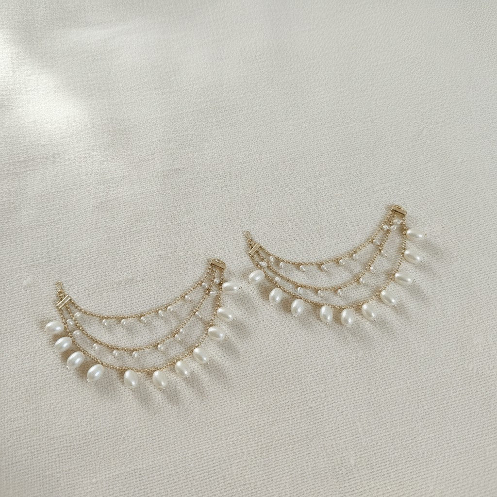 Pair of gold and pearl earrings on a light gray background
