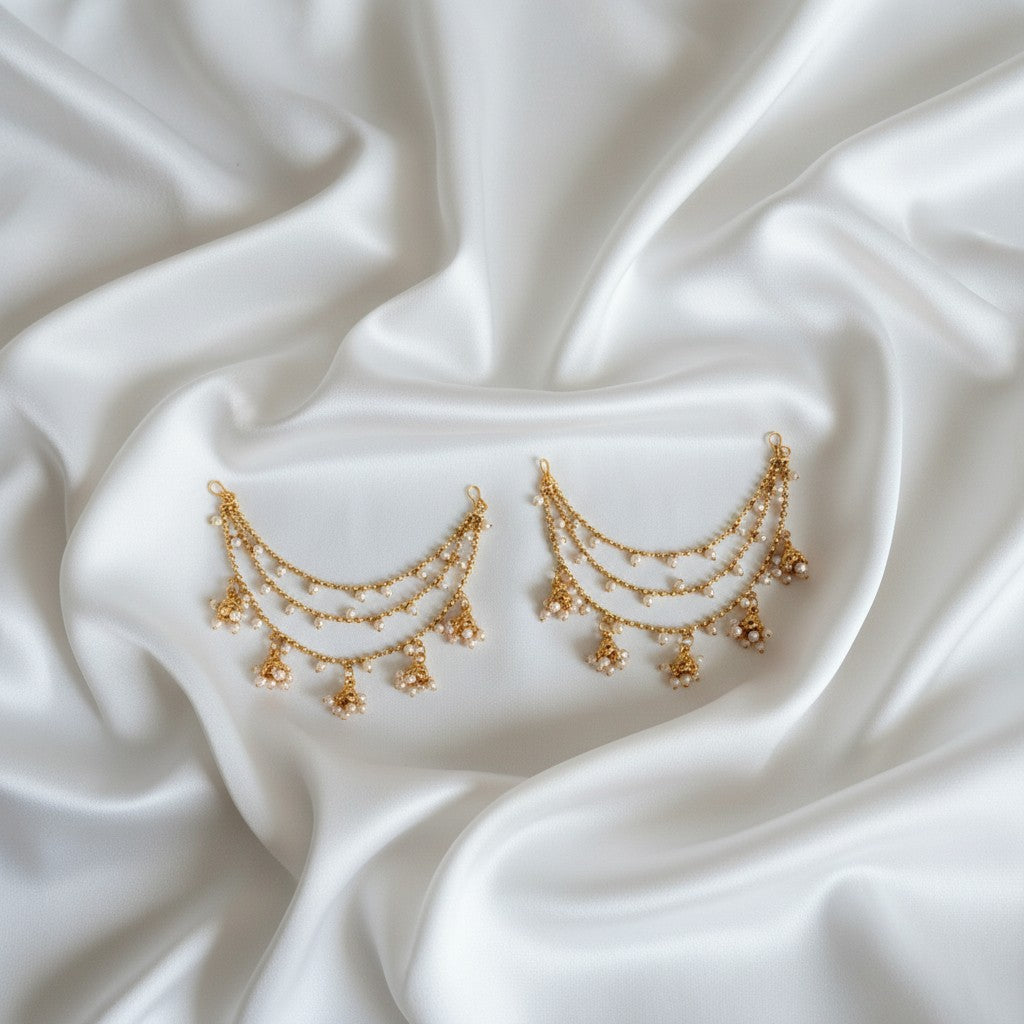 Gold earrings on a white satin fabric