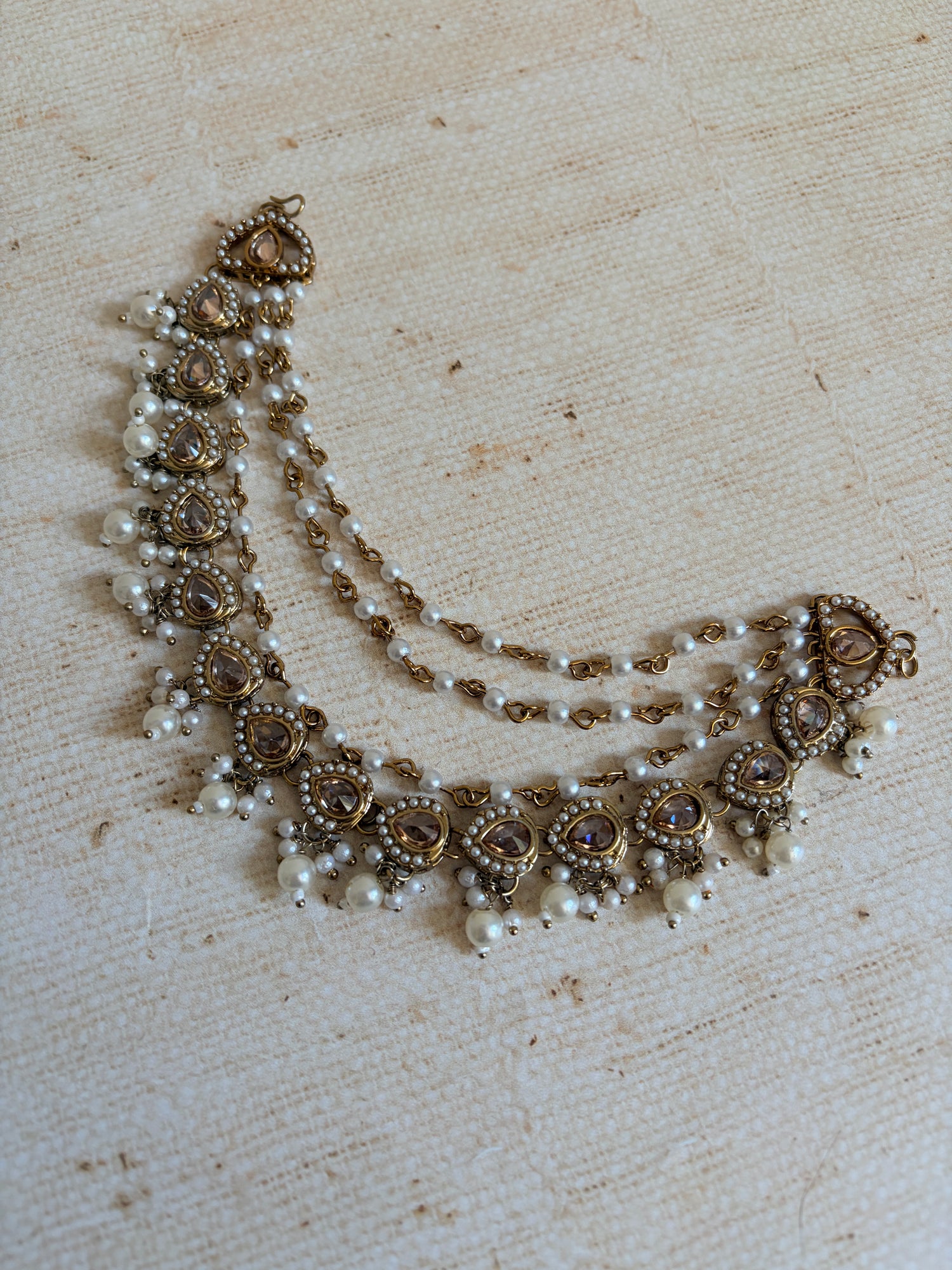 Decorative necklace with pearls and floral designs on a textured beige background