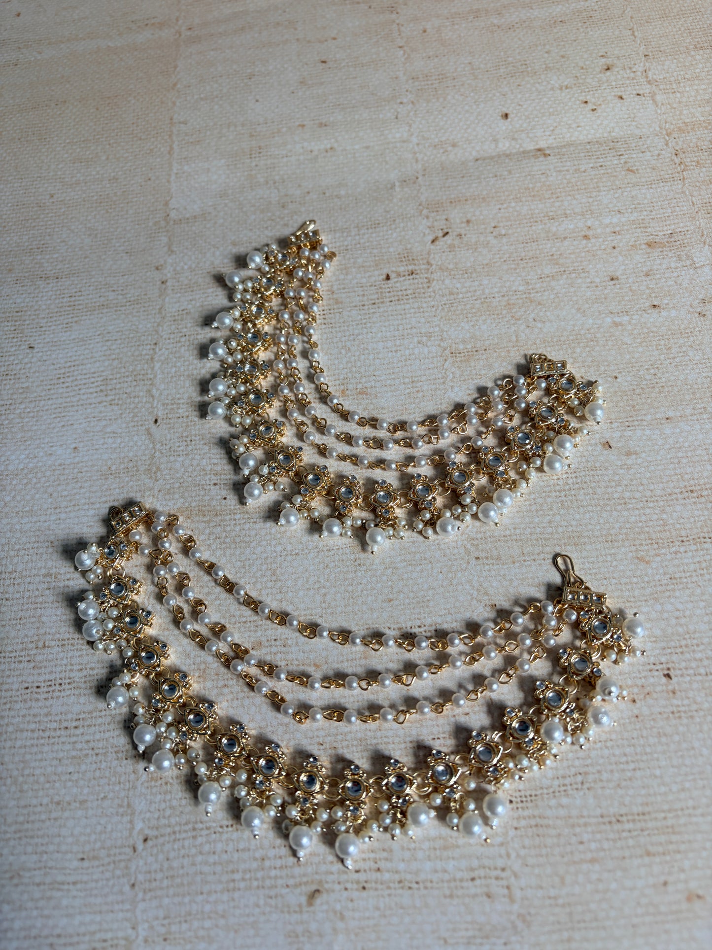 Gold and pearl necklace on a textured beige surface
