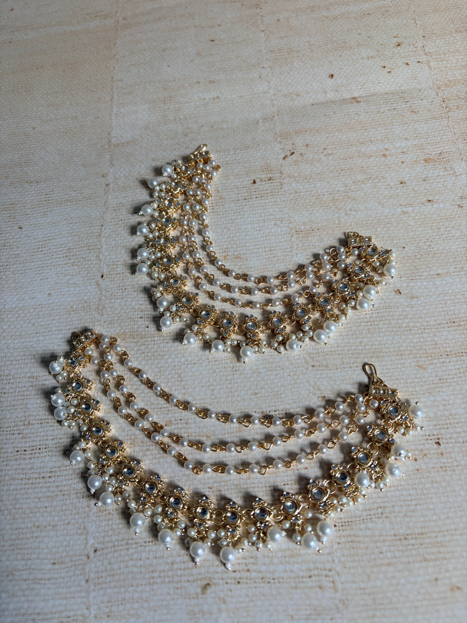 Gold and pearl necklace on a textured beige surface