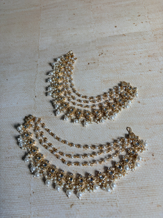 Gold and pearl necklace on a textured beige surface
