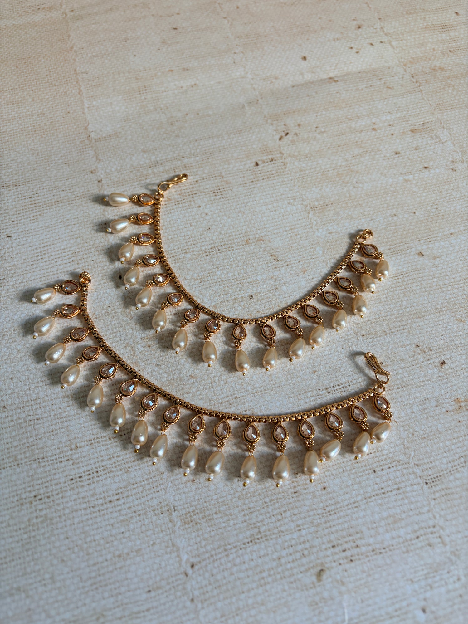 Gold and pearl necklace on a textured beige background
