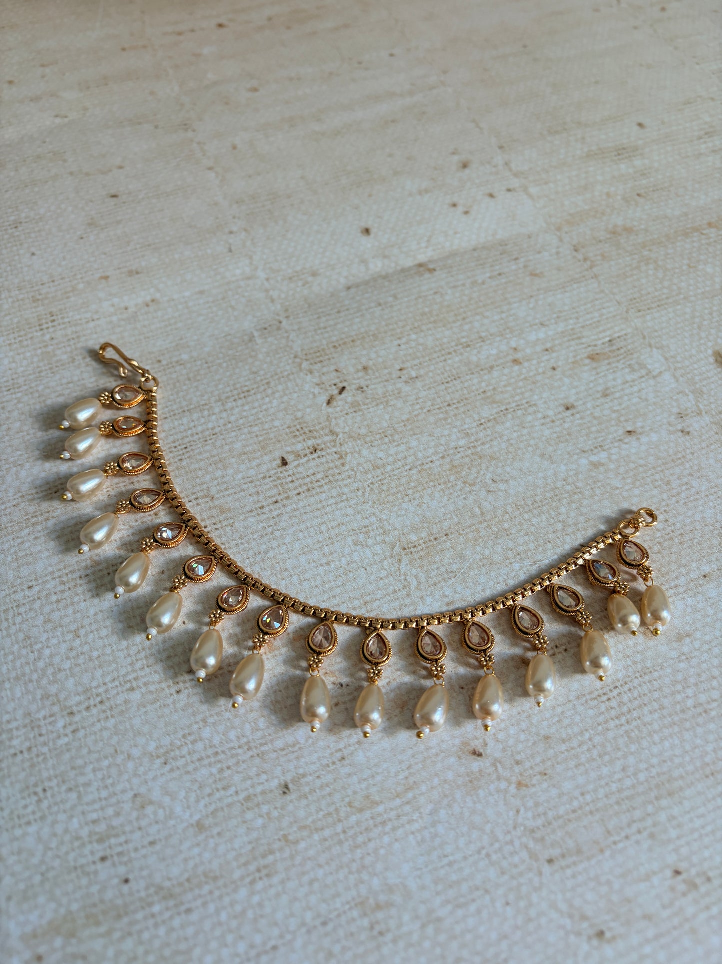 Gold and pearl necklace on a textured beige background