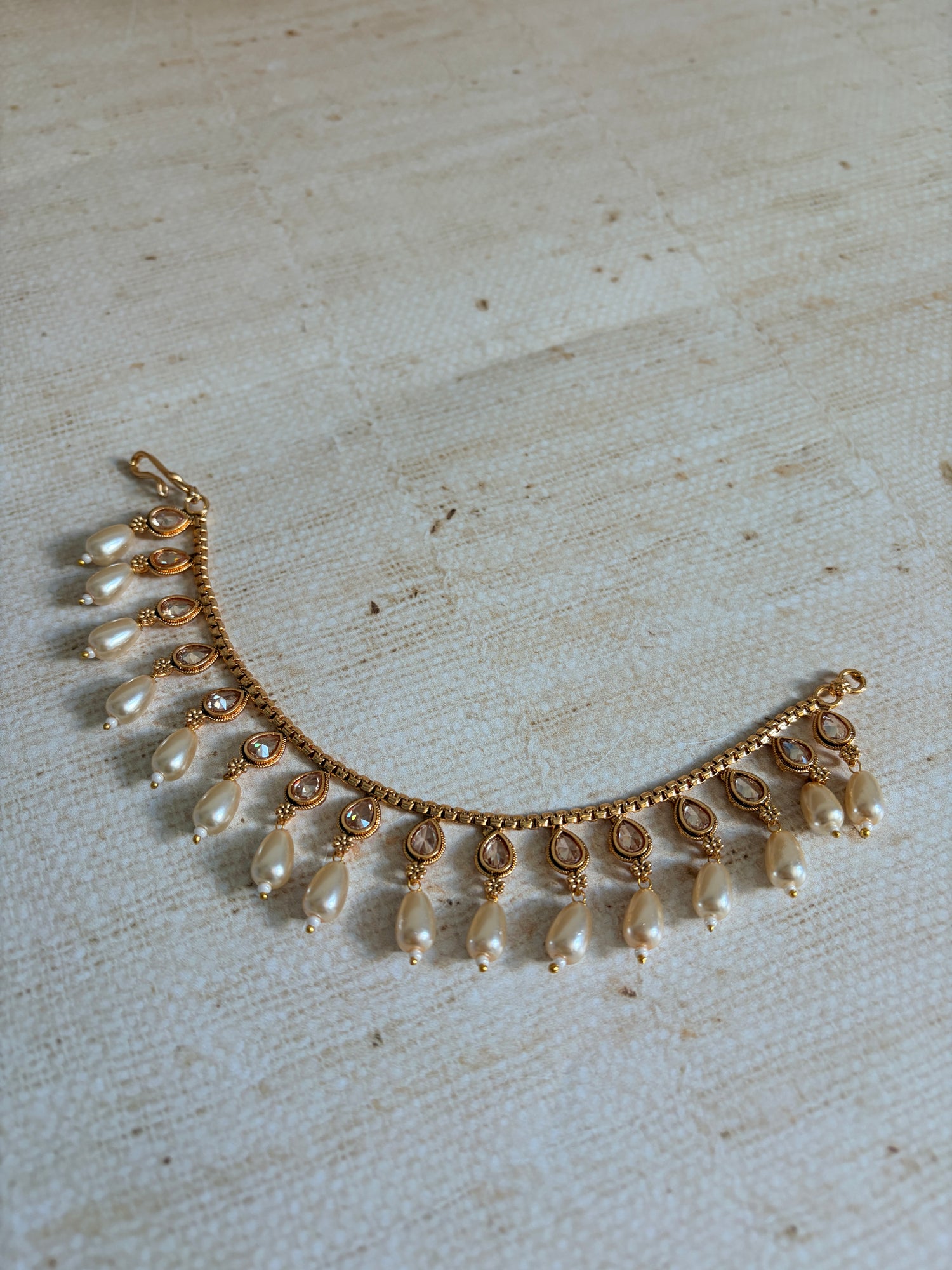 Gold and pearl necklace on a textured beige background