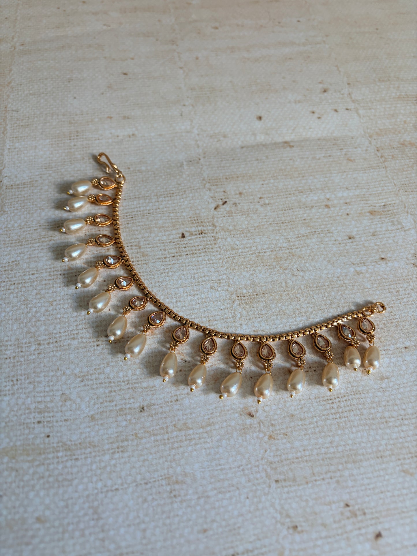 Gold and pearl necklace on a textured beige background