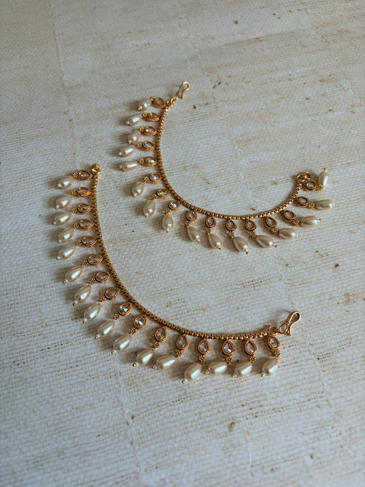 Gold and pearl necklace on a textured beige surface