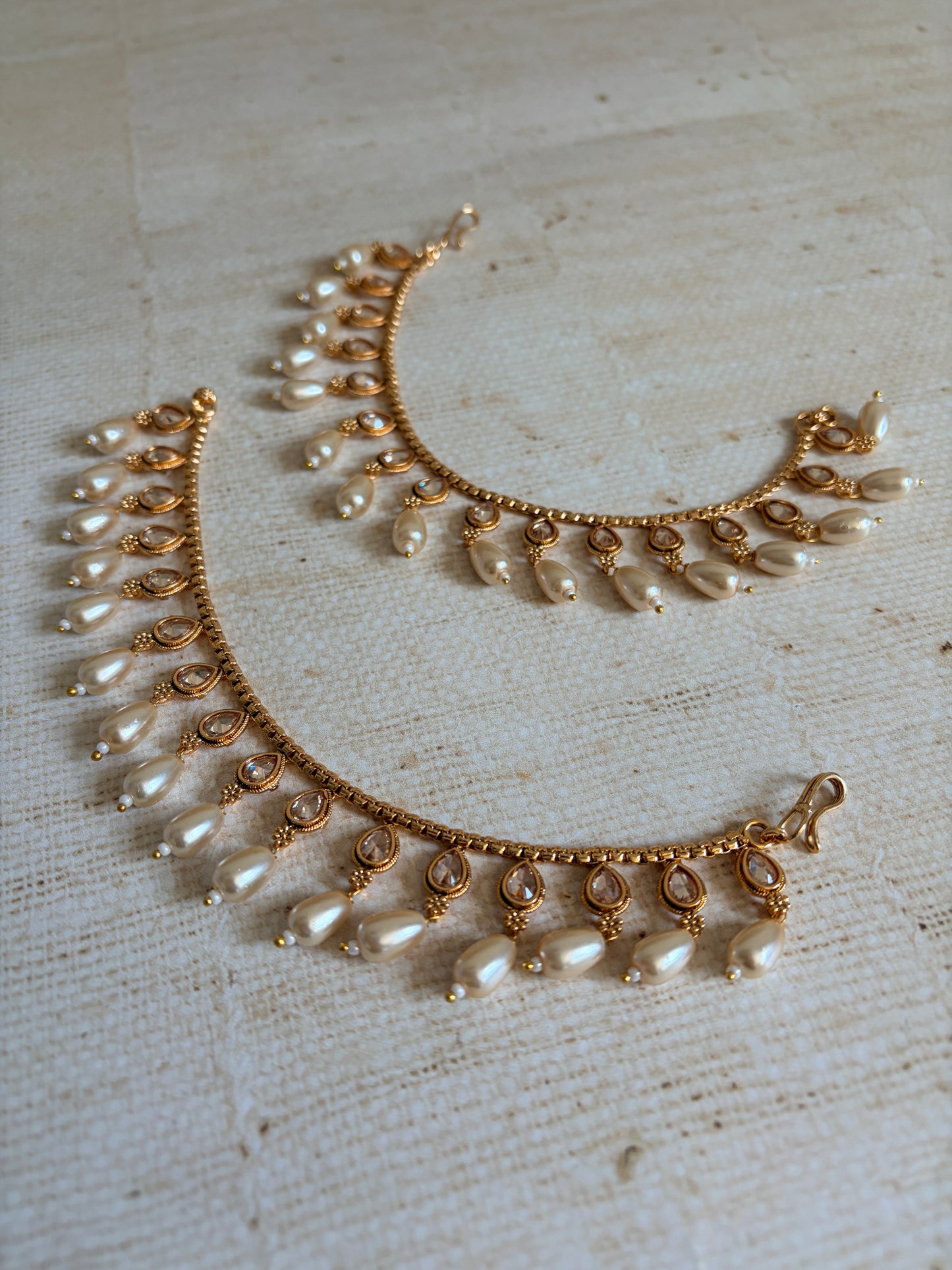 Gold and pearl necklace on a textured beige background