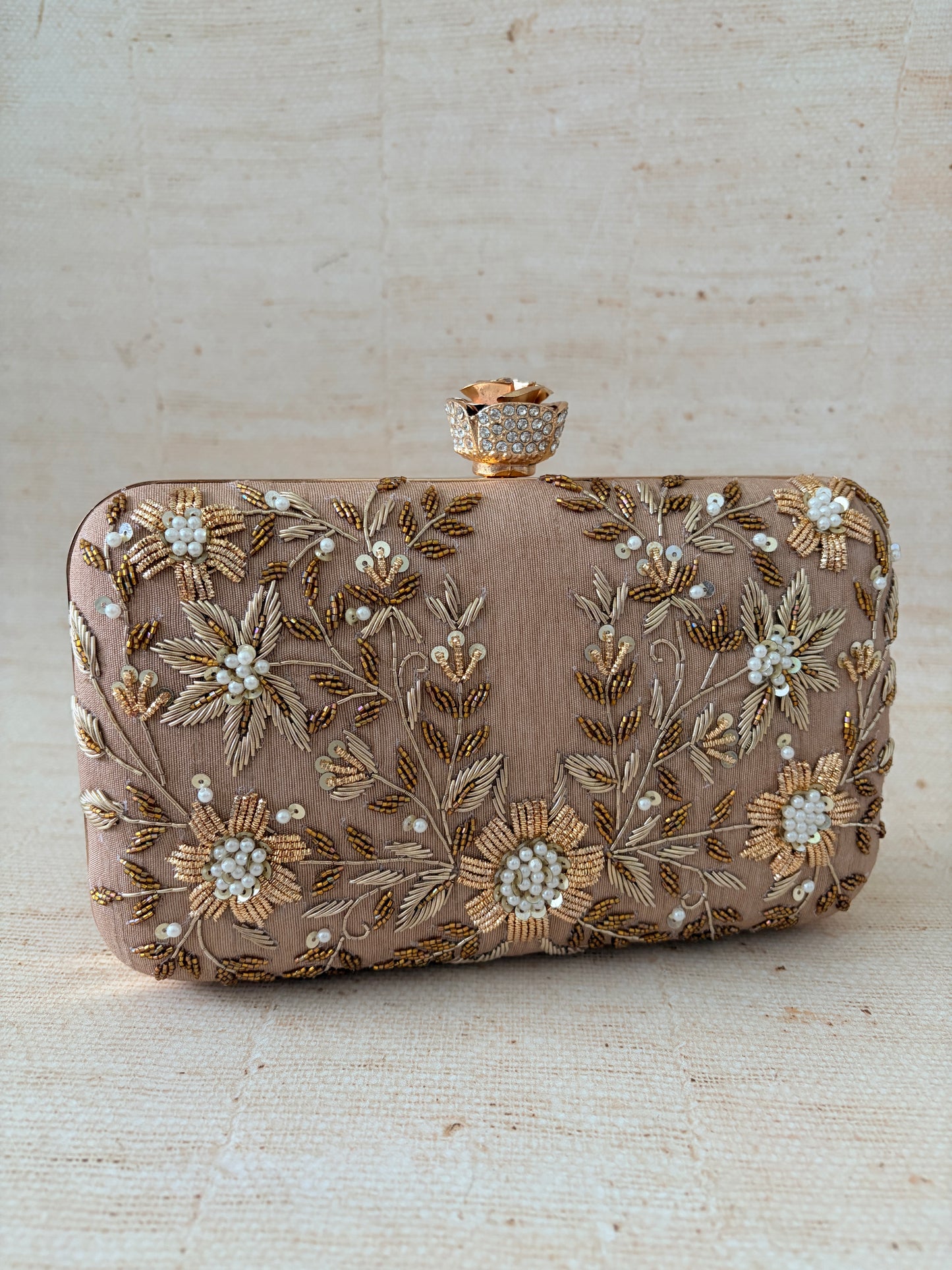 Decorative clutch bag with floral embroidery on a light wooden surface