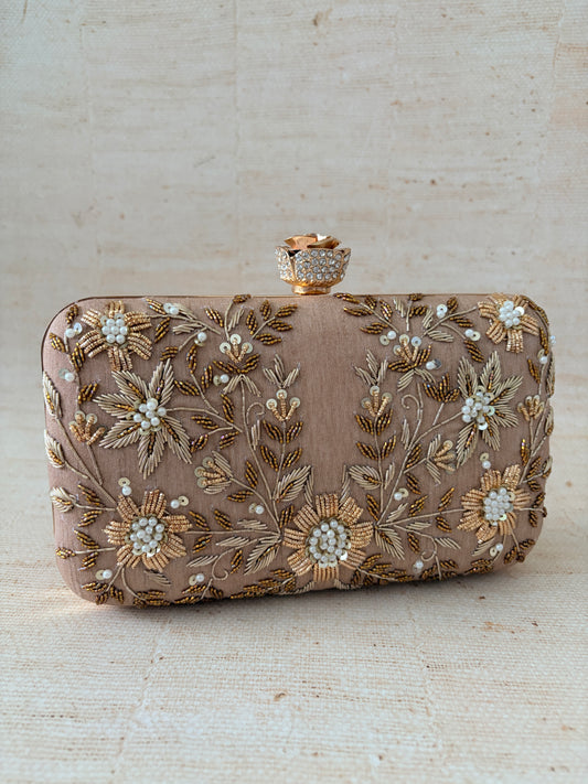 Decorative clutch bag with floral embroidery on a light wooden surface