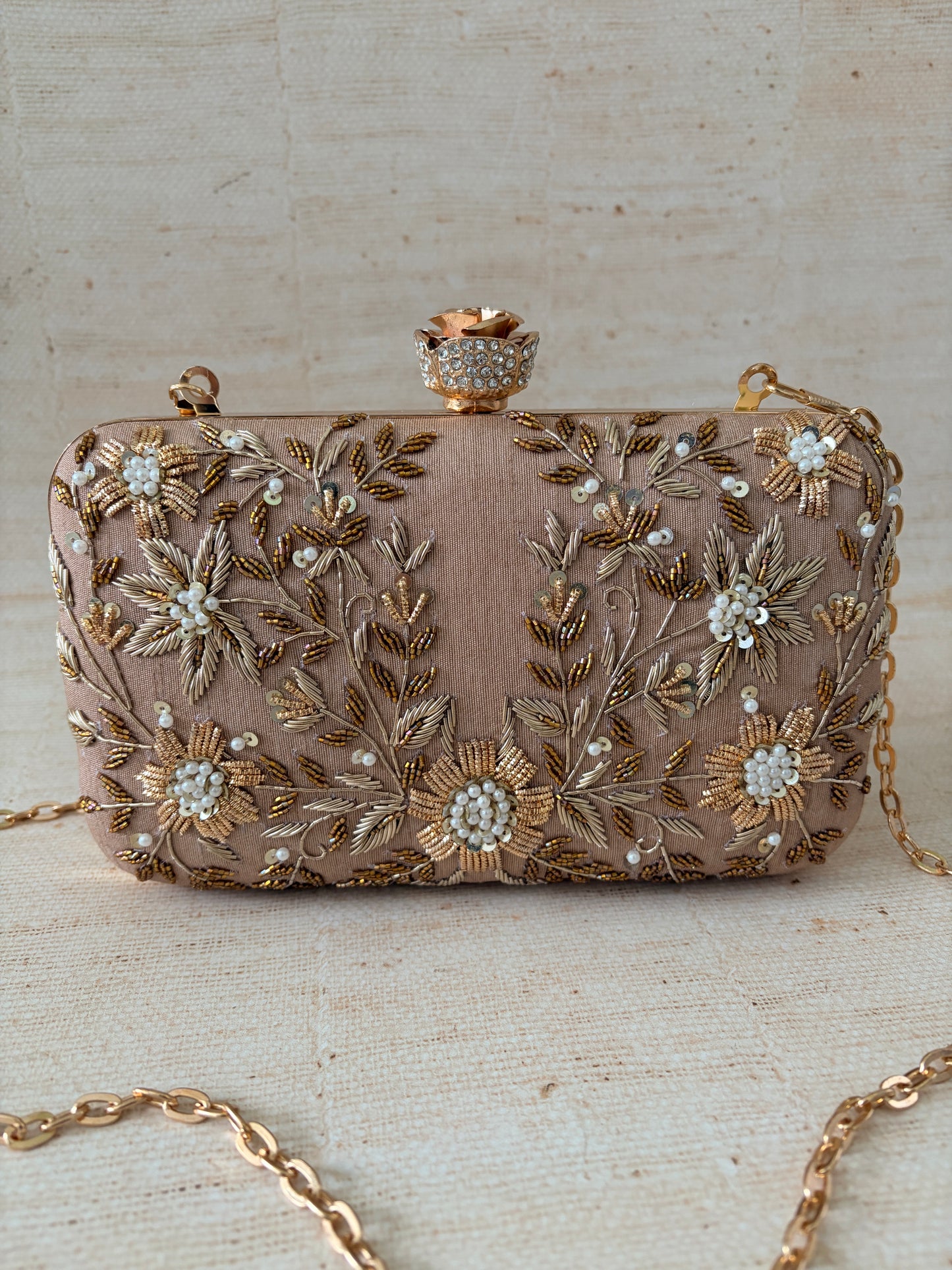 Decorative clutch bag with floral embroidery on a textured surface