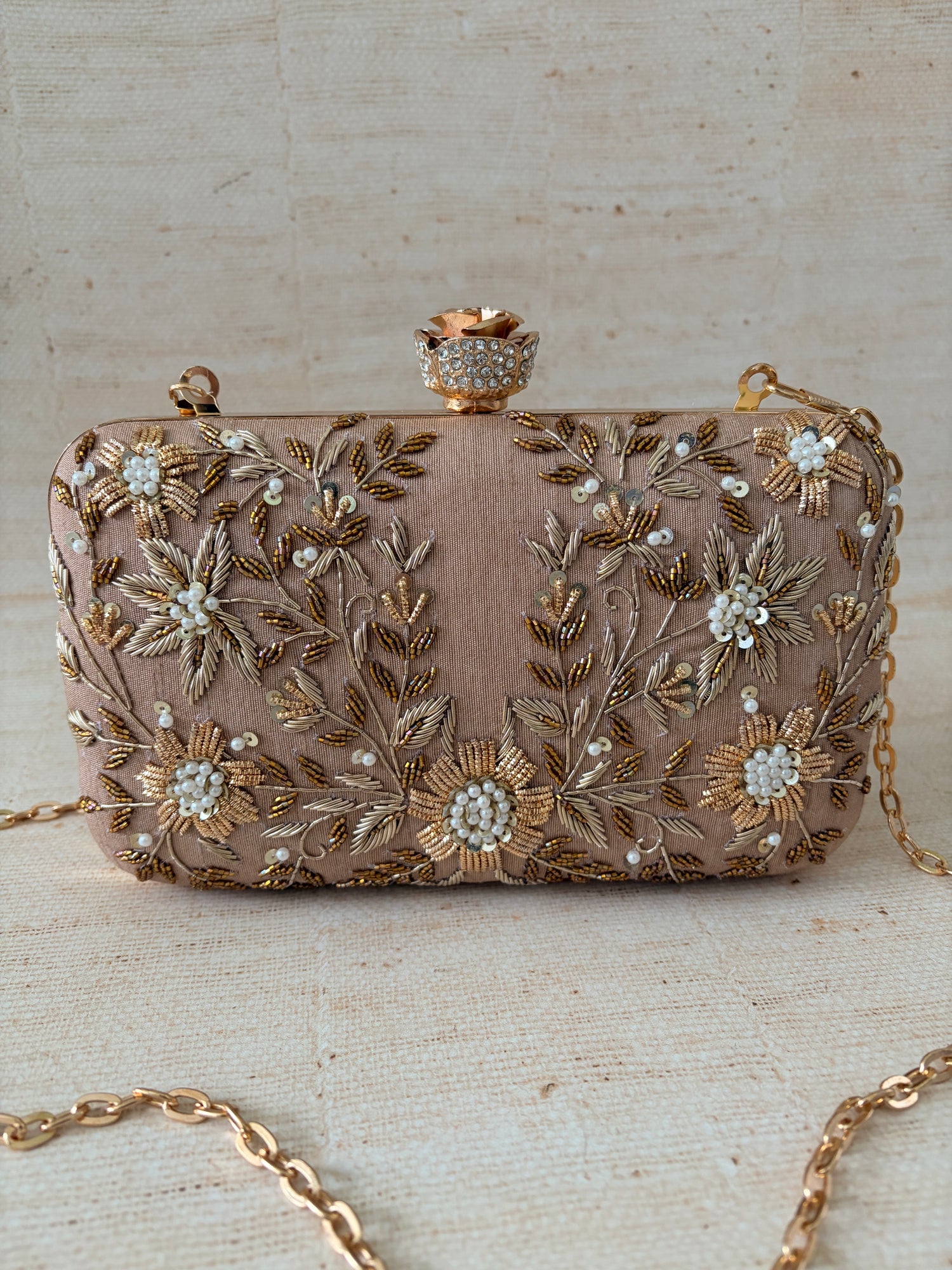 Decorative clutch bag with floral embroidery on a textured surface