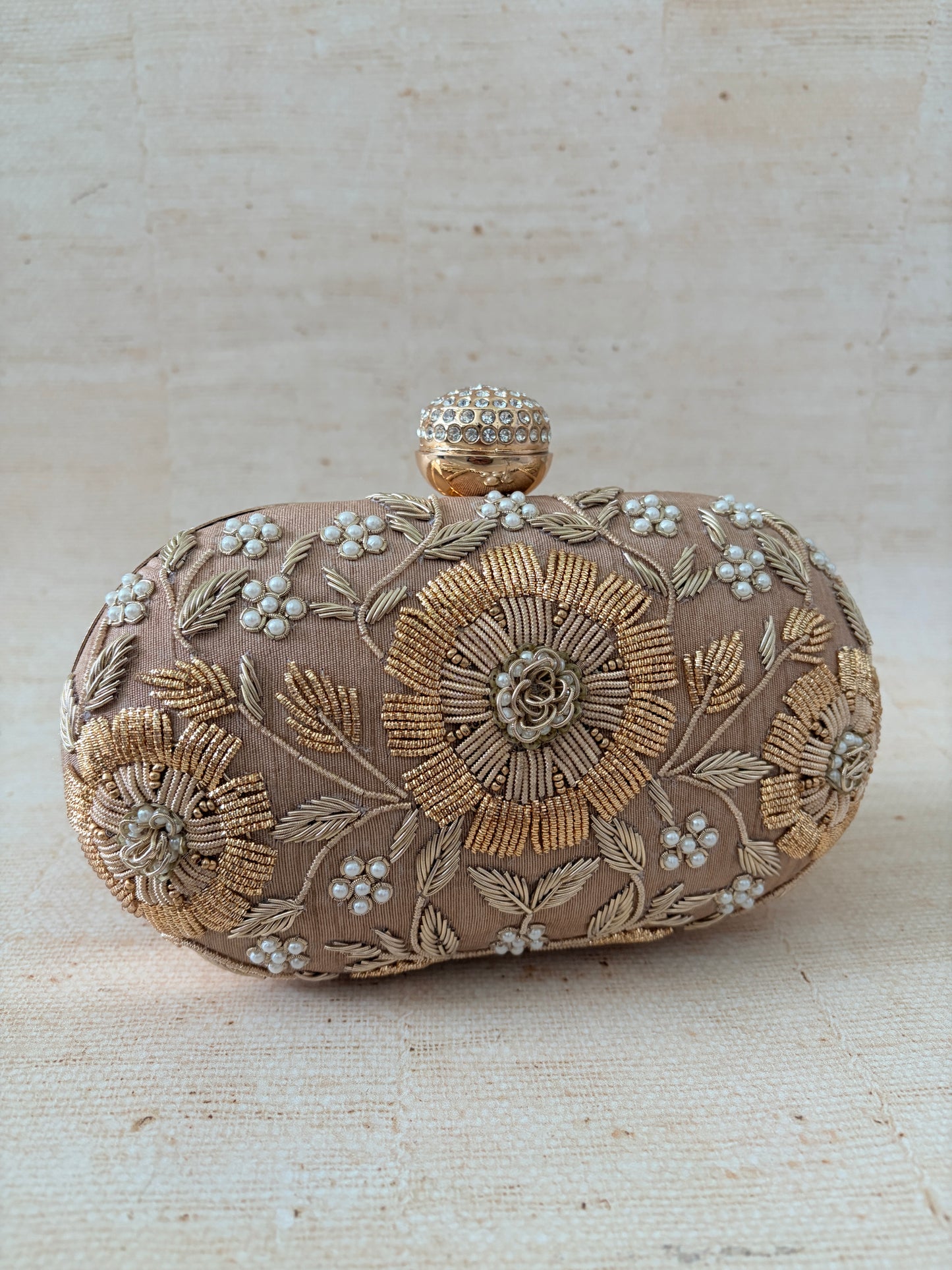 Decorative clutch bag with floral embroidery on a beige background