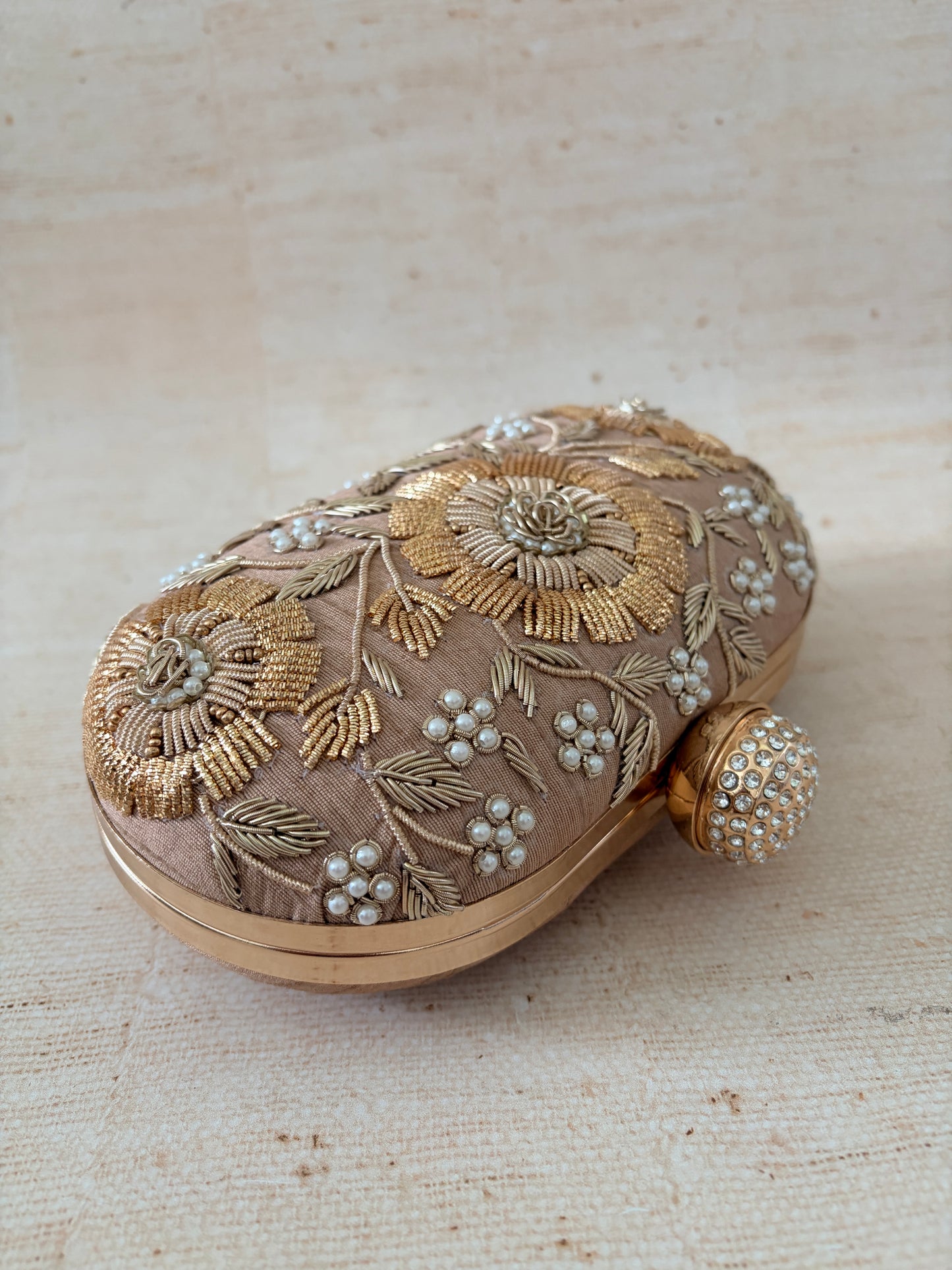 Decorative handbag with floral embroidery on a textured beige background