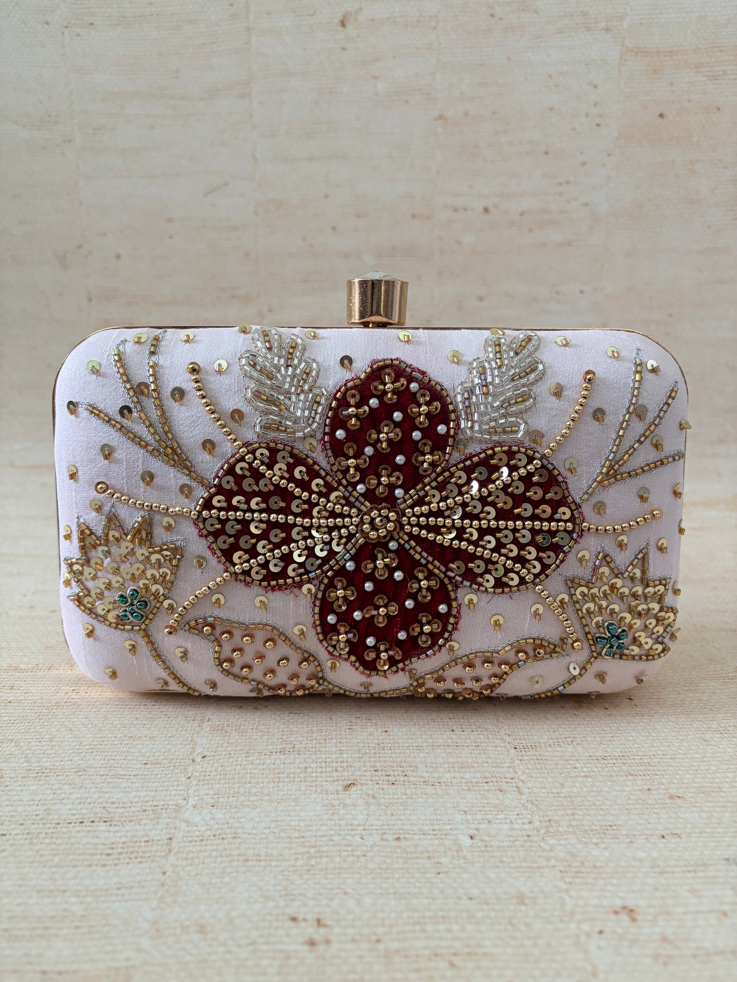 Decorative clutch with floral patterns and beading on a textured surface