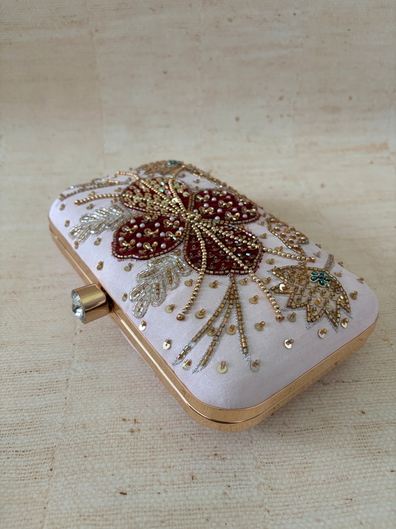 Decorative clutch with floral embellishments on a beige fabric background