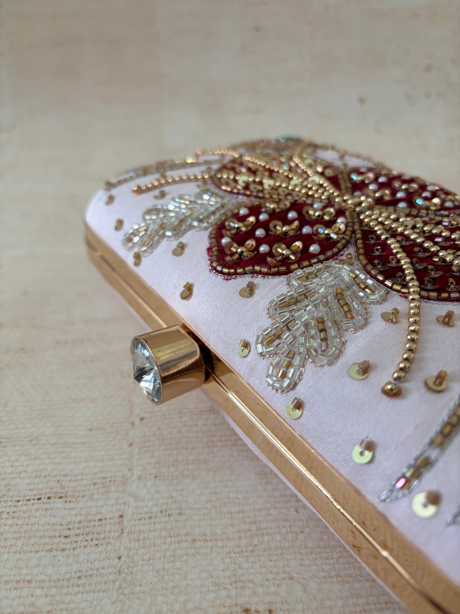 Decorative clutch with gold and red embellishments on a beige background