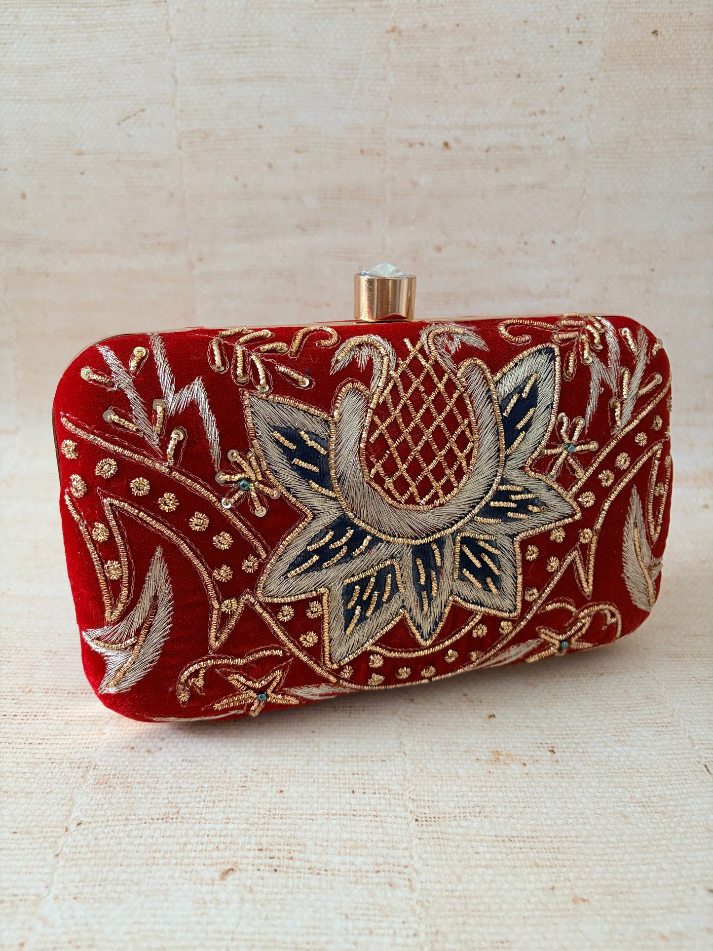 Decorative red pouch with floral embroidery on a beige background