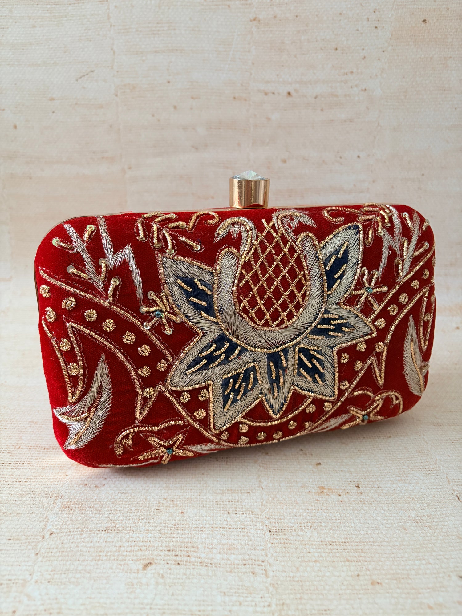 Decorative red pouch with floral embroidery on a beige background
